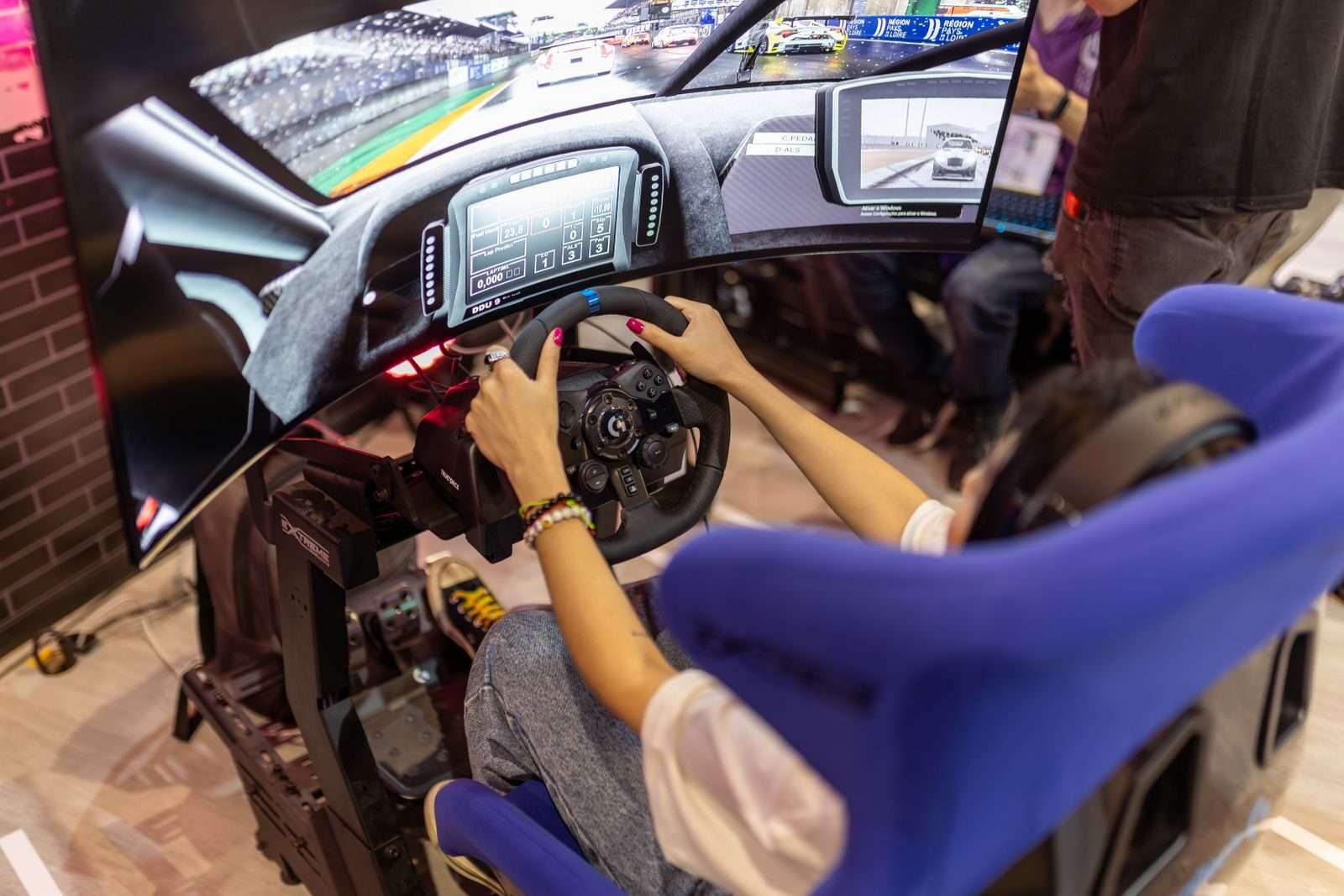 Person using a realistic VR racing simulator at a gaming event, focused on the immersive experience.